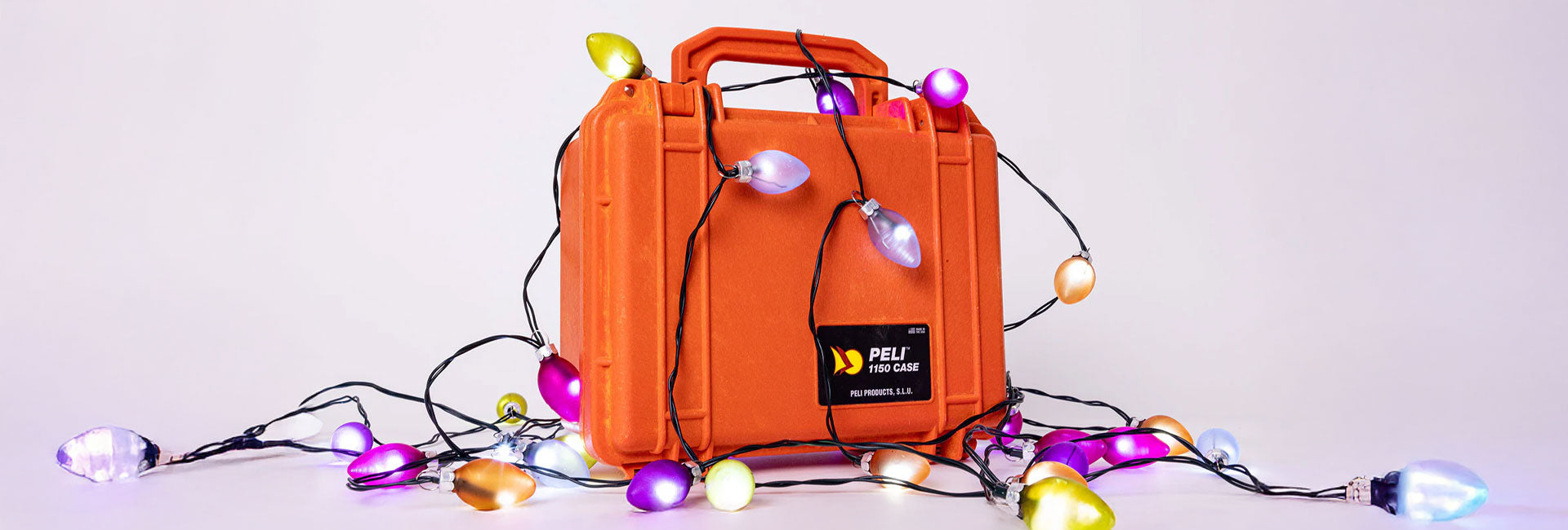 Orange 1150 Peli Protector case with colorful string lights on a light gray background