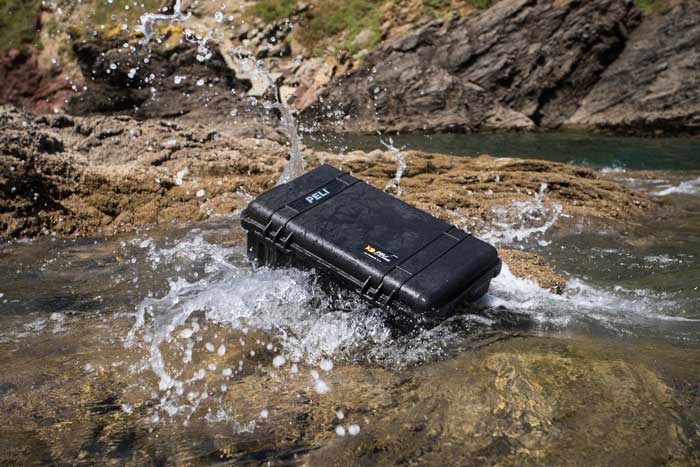 A black Peli 1510 case in a small steam flowing through a rocky landscape.