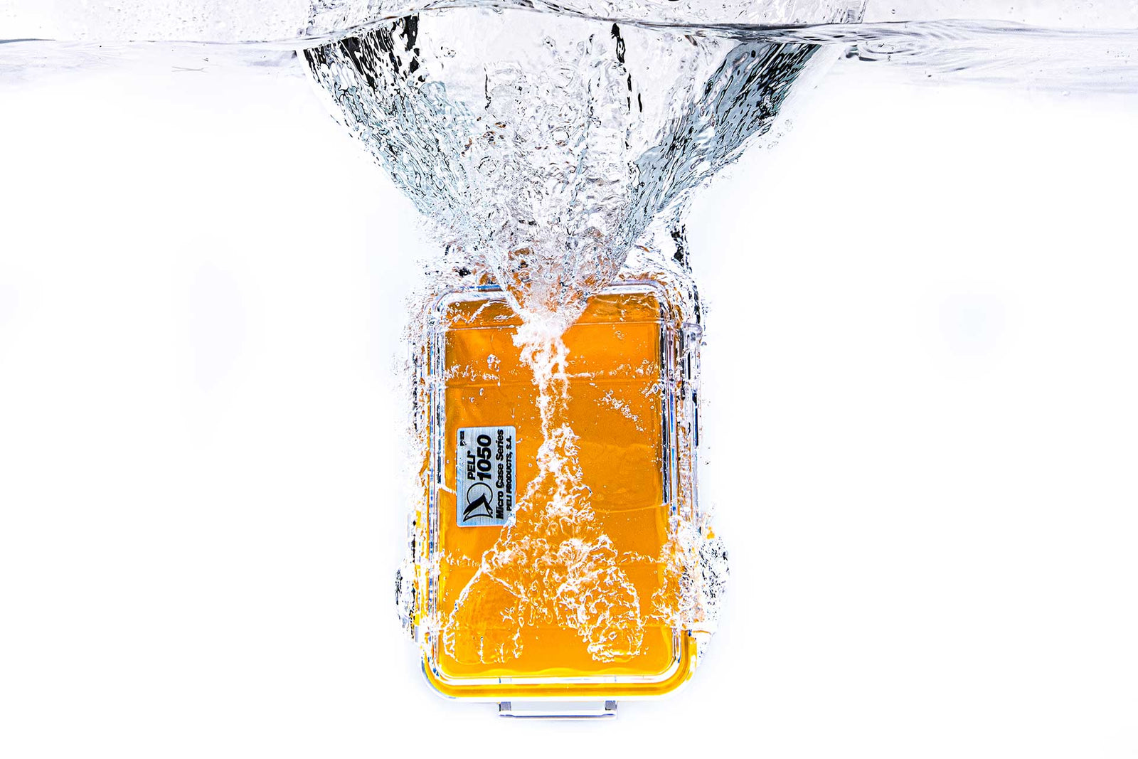 A clear and yellow Peli 1050 Micro Case being dropped into water, creating a splash.